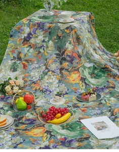 Detailed view of floral oil painting style picnic mat laid on lush green grass