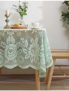 Detail of light green lace tablecloth with hollow floral pattern and wavy edges