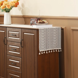 Vintage beige crochet table runner with tassels on a wooden cabinet, retro home decor