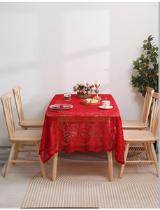 Detail of red lace tablecloth showing intricate hollow floral patterns and wavy edges
