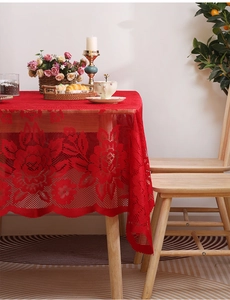 Close-up of red hollowed-out lace tablecloth with floral patterns and scalloped edges