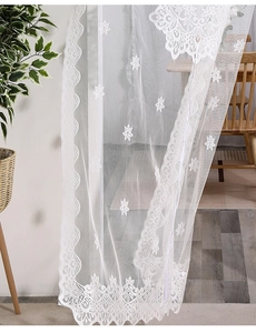 Detailed close-up of white lace curtain with embroidered star patterns and wavy hem edges