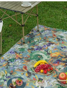 Floral oil painting picnic mat on green grass with tea set and fruit in outdoor setting