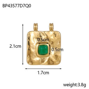 Detail view of vintage gold plated pendant with green stone and hammered metal texture