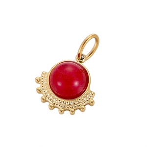 Macro detail of a fan-shaped gold titanium pendant with a vibrant red stone inlay