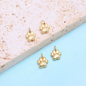 Detailed view of four golden paw charms with zircon accents for jewelry making