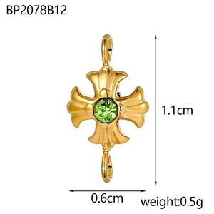 Dettaglio macro di un connettore per gioielli a croce dorata da 1,1 cm con pietra verde