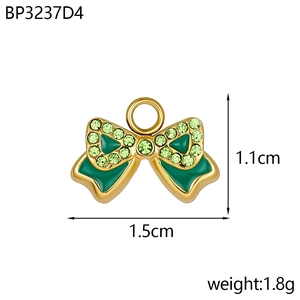 Détail d'un pendentif nœud doré avec émail vert et strass brillants sur fond blanc