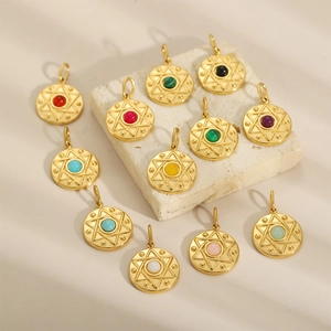 Golden round starburst pendants with colorful gemstones on a stone background