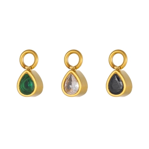 Macro shot of rose gold water-drop charms with green, white, and black pear-cut gemstones