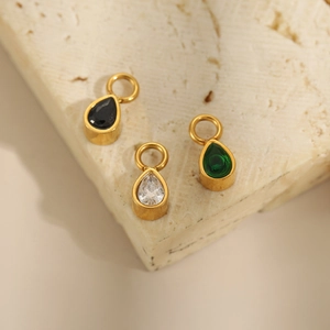 Detailed macro view of teardrop pendants in gold titanium steel with colored gemstones