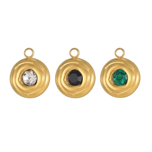 Detailed view of three round gold pendants with white, black, and emerald green gemstones