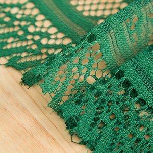 Green vintage lace table runner with hollow floral weave and tassels on wooden table