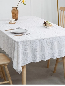 Detailed view of white floral jacquard tablecloth with elegant scalloped lace edges