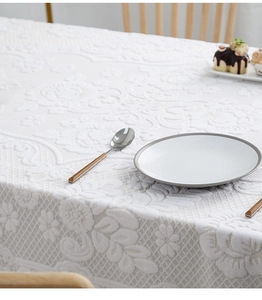 Detail of white floral jacquard tablecloth with elegant hollow lace and embossed texture