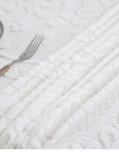 Close-up of white 3D textured bubble fabric tablecloth with elegant lace edge and fork
