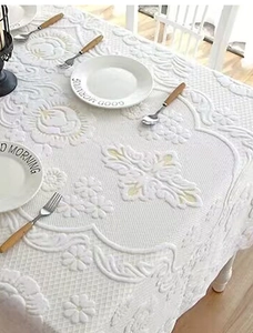 Detail of white embossed floral tablecloth with lace edges and jacquard rose texture