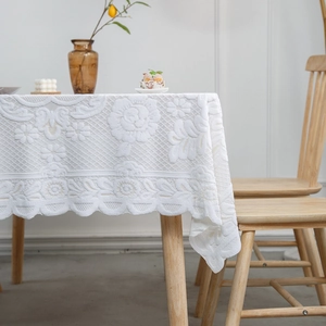 Elegant white lace tablecloth with floral hollow embroidery on a wooden table