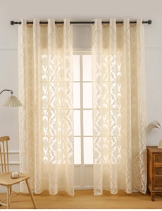 Detail of cream damask lace curtain with grommet top hanging on black metal rod