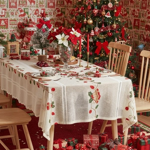 Christmas lace tablecloth with red bells and holly leaves on festive dining table set
