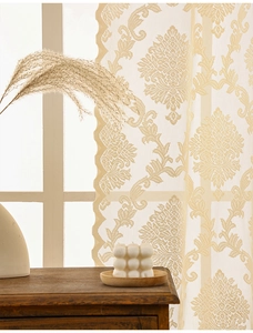 Close-up of beige lace curtain with elegant Damascus floral patterns and scalloped edges