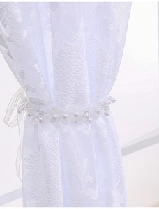 Close-up of elegant pearl and acrylic flower tieback on white lace curtains