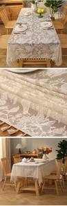 Detailed close-up of cream lace tablecloth featuring floral embroidery and tassel fringe