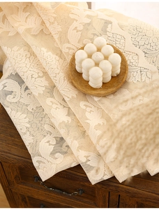 Detail of vintage beige floral lace fabric with intricate embroidery on a wooden cabinet