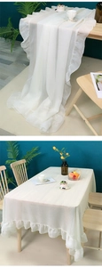 Close-up of white rectangular tablecloth with elegant ruffle edge and embroidery detail