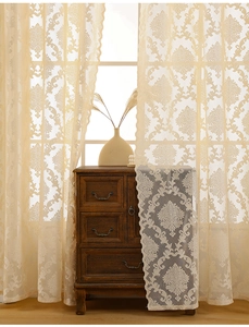 Detailed close-up of beige lace curtains with classical Damascus floral patterns