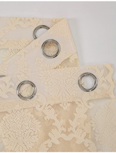 Close-up of beige lace curtain with floral patterns and silver metal grommets