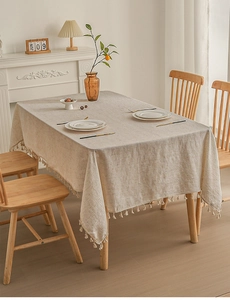 Detail of minimalist linen tablecloth with white tassels and natural woven texture