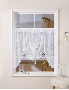 Detail of white lace cafe curtain with floral embroidery and elegant gathered drawstrings