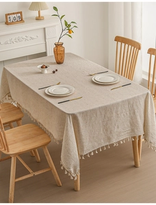 Close-up of minimalist oatmeal linen tablecloth with decorative tassel fringe edges