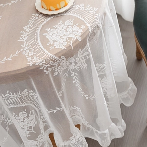 White lace tablecloth featuring intricate rose embroidery and elegant ruffled edges on round table