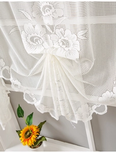 Detail of beige lace cafe curtain with delicate floral embroidery and wavy scalloped edges