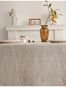 Detail of beige linen tablecloth featuring a coarse woven texture and elegant drape
