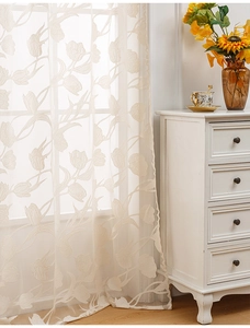 Close-up of beige tulip lace curtain with intricate floral patterns and sheer texture