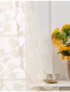 Detail of tulip lace curtain with floral relief texture and soft lighting in a room