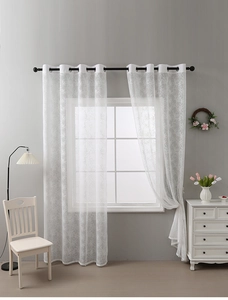 Detail of white sheer curtain featuring elegant branch embroidery and metal grommets