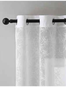 Detail of white lace curtain with embroidered branch pattern and silver grommet top