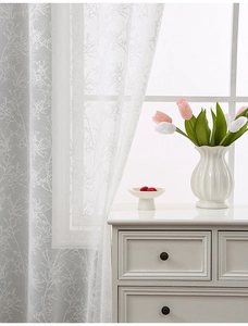 Macro detail of white lace curtain featuring delicate branch patterns for home decor