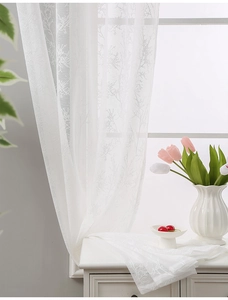 Detail of white lace curtain with delicate branch pattern and semi-transparent texture