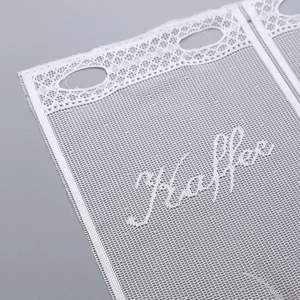 Detail of white mesh kitchen cafe curtain featuring Kaffee embroidery and lace trim