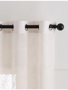Detail of white lace curtain with branch patterns and silver metal eyelets on black rod