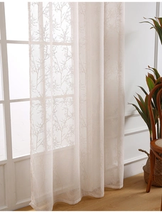 Close-up of semi-transparent beige lace curtain with delicate branch pattern texture