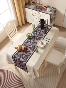 Detail of dark floral table runner with red and blue paisley patterns on beige tablecloth