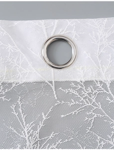 Detail of white lace curtain showing tree branch patterns and silver metal grommets
