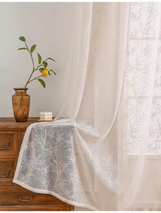 Close-up of elegant white lace curtain with branch patterns draped on a wooden cabinet