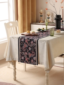 Close-up of black floral table runner with colorful paisley patterns on a wooden table